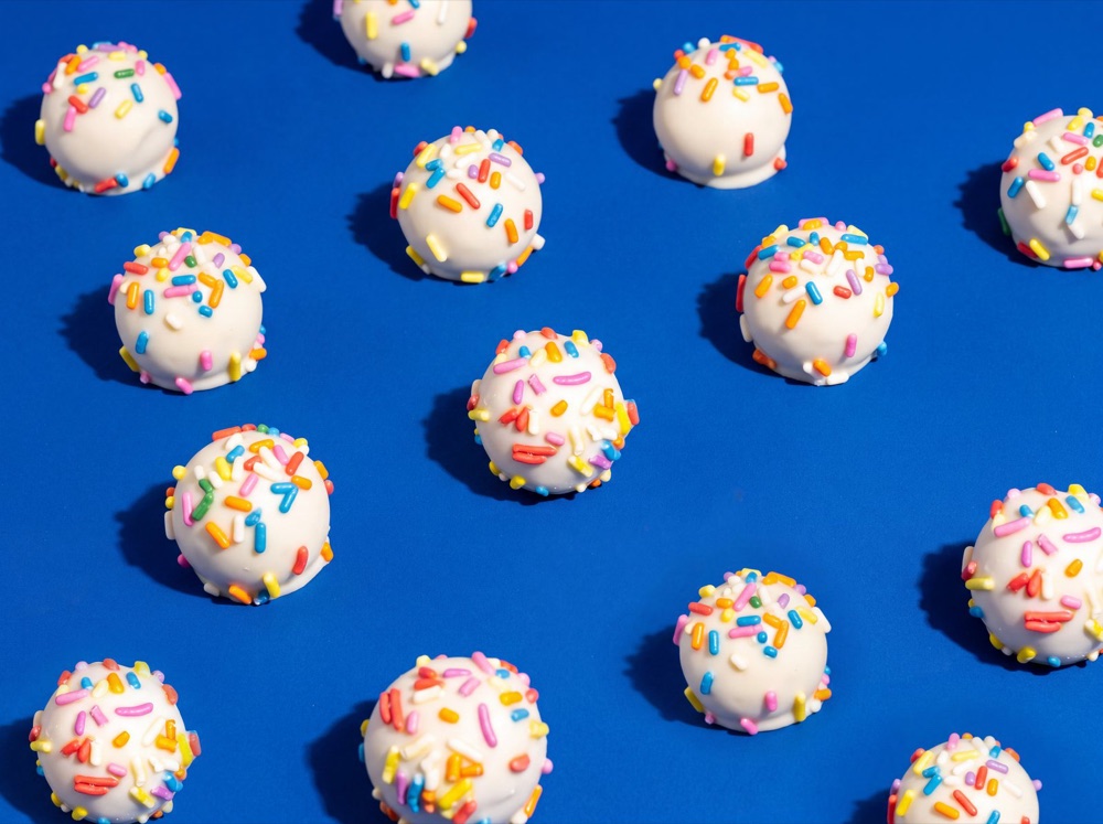Birnn Chocolates Birthday Cake truffles scattered on cobalt blue