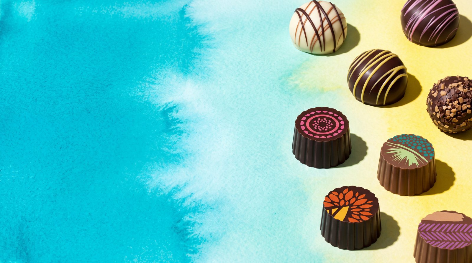Birnn Chocolates homepage hero band, watercolor wash with a scattered variety of truffles